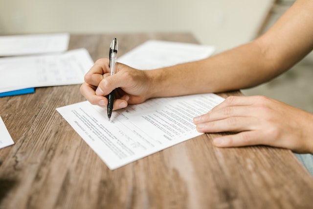 person filling out an insurance policy with a black pen