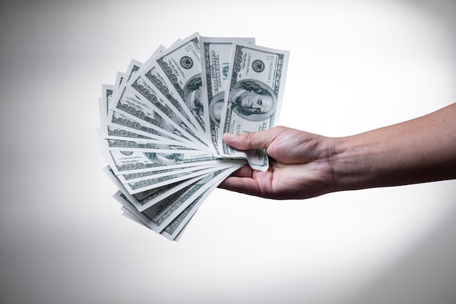 person holding a bunch of one hundred dollar bills