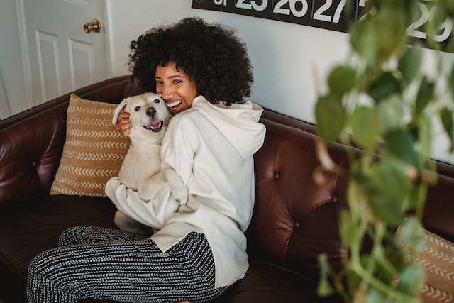 tenant sitting on their brown leather couch holding their terrier puppy and smiling